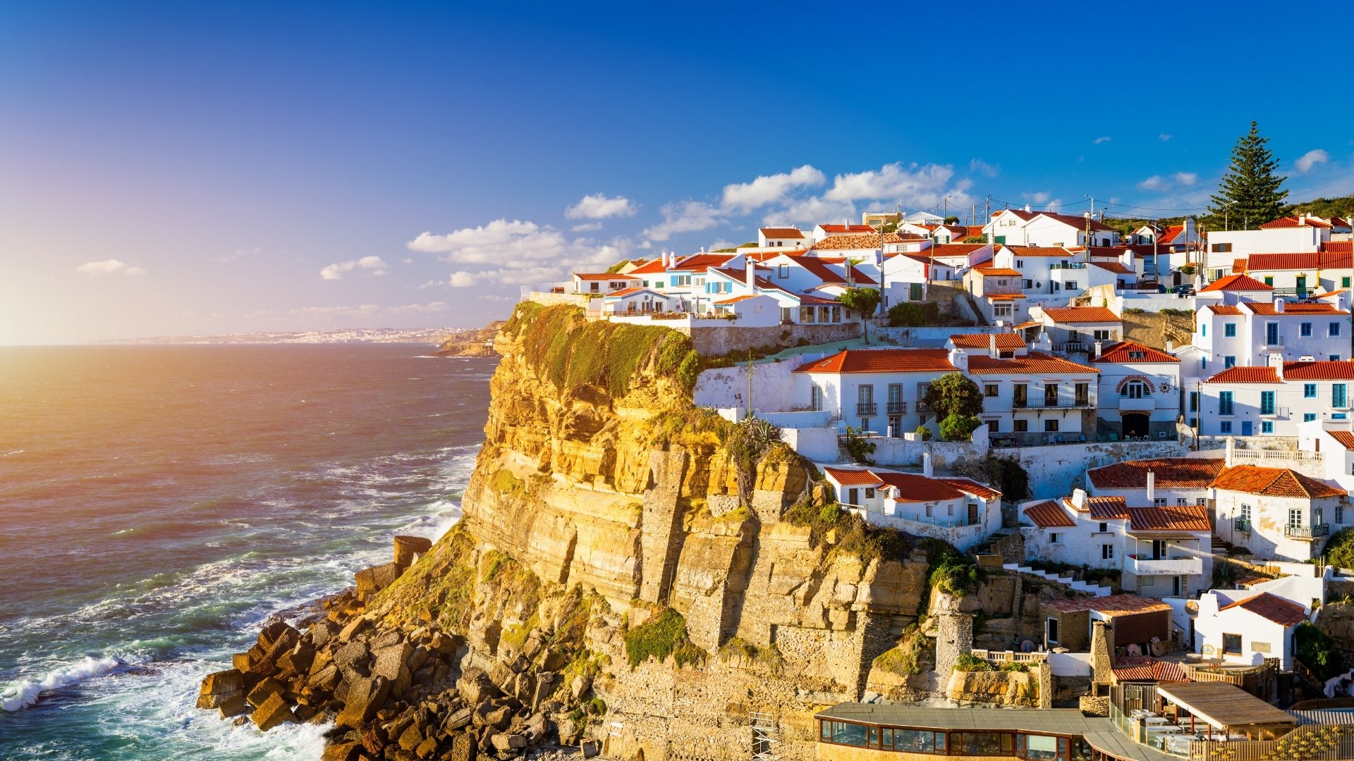 Azenhas do Mar is a picturesque seaside town located on a cliff in Sintra, Portugal, characterized by its white houses with red roofs overlooking the ocean.